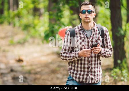 Hipster junger Mann mit Rucksack mit Smartphone auf wunderschönem Naturerlebnis.Reisekonzept. Reisen im Freien. Reisen und erkunden. Backpa Stockfoto