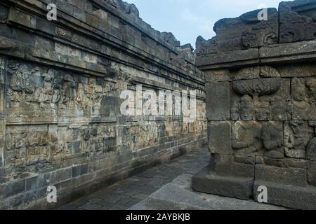 Steinbass-Reliefschnitzereien an einem schmalen Durchgang an einer unteren Plattform des Borobudur-Tempels (UNESCO-Weltkulturerbe, neuntes Jahrhundert), dem größten Budd Stockfoto