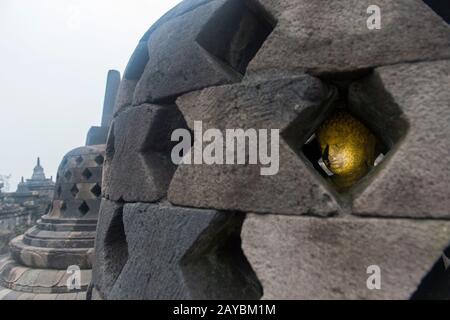 Blick auf eine Buddhastatue in einem perforierten Stupa auf der oberen Plattform des Borobudur-Tempels (UNESCO-Weltkulturerbe, neuntes Jahrhundert), dem größten B Stockfoto