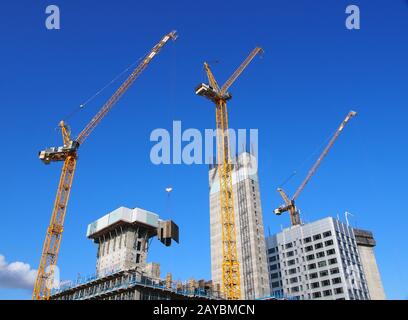 Blick auf das Stadtbild von hohen Turmkränen, die an großen Baustellen gegen einen blauen Himmel in leeds england arbeiten Stockfoto