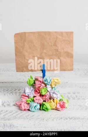 Quadratische Mahnung über einem Stapel zerknitterter Papiere, die von einer blauen Wäscheklammer befestigt werden. Verschiedene Blätter, die unter einer leeren Farbe gestapelt sind Stockfoto