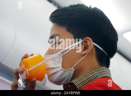 PIC zeigt: Der Flugbegleiter entfernt nicht einmal seine Maske, um zu zeigen, dass er bei Sicherheitsdemonstrationen Sauerstoff geben Sollte. Reisende, die am BKK-Flughafen ankommen, Stockfoto