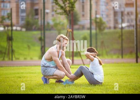 Sit ups Fitness-Paar, das trainiert, sitzt draußen im Gras. Passen Sie Leute, die Kreuztraining ausarbeiten. Frau, die Bauchkräschen macht Stockfoto