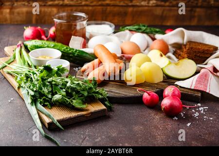 Prozess der Herstellung Okroshka Suppe. Häckseln, Rettich, Wurst und andere Zutaten auf Holz Schneidebrett Stockfoto