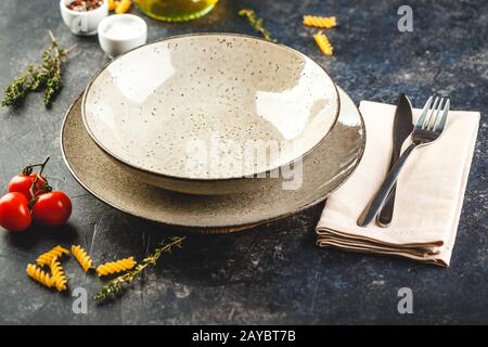 Tabelle Einstellung mit Besteck, Pasta, Tomaten und Kräutern Stockfoto