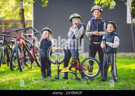 Kindermechaniker, Fahrradreparatur. Glückliche Kinder, die am sonnigen Tag gemeinsam im Freien Fahrrad machen. Fahrrad-Reparaturkonzept. Teamarbeit berühmt Stockfoto