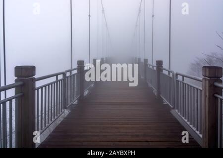 Die Hängebrücke aus Holz am Berg Tianmen verschwindet in sehr starkem Nebel oder Nebel. Halloween oder Horror c Stockfoto