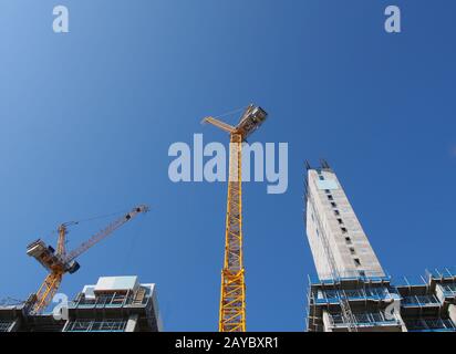 Blick auf hohe Turmkräne, die auf großen Baustellen gegen einen blauen Himmel in leeds england arbeiten Stockfoto