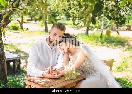 Schönes Paar Neuvermählte, fröhlicher und fröhlicher Moment. Brautpaar sitzen am Tisch für zwei Personen im Wald. Konzept Romantik Datum. Stockfoto