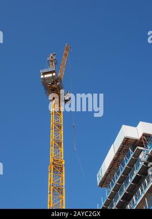 Blick auf einen hohen Turmkran, der auf großen Baustellen gegen einen blauen Himmel arbeitet Stockfoto