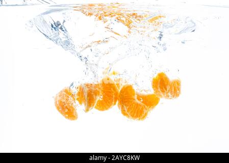 Isolierte fallende orange Segmente in Wasser. Geschälte Stück orange Frucht im Wasser auf weißem Hintergrund Stockfoto
