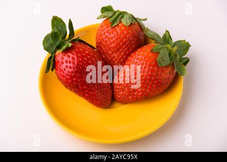 Drei Erdbeeren auf einem gelben Teller Stockfoto