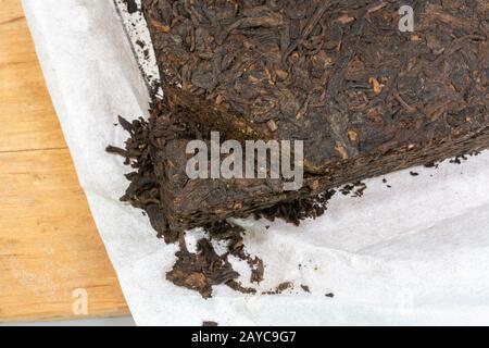 Chinesischer Yunnan Pu Erh Teeblock in weißem Seidenpapier verpackt Stockfoto