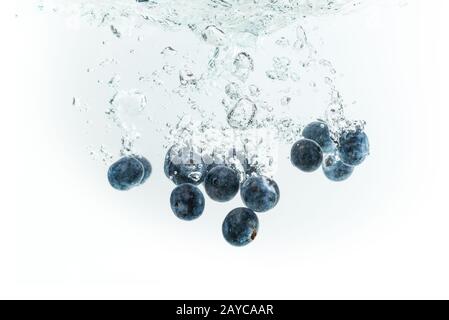Unter Wasser sinkende Blaubeeren mit auf weißem Hintergrund isolierten Luftblasen Stockfoto