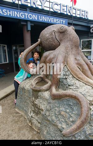 Kinder, die auf die riesige Tintenstatue vor dem SEA Discovery Centre, einem öffentlichen Aquarium, in der Stadt Poulsbo im skandinavischen Stil in Ki klettern Stockfoto