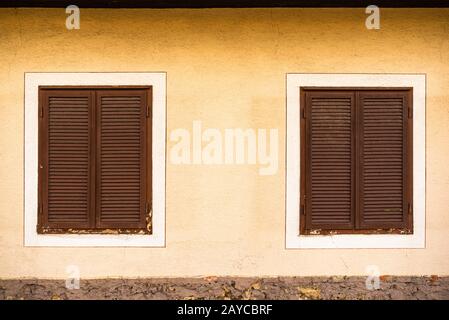 Zwei Holzfenster mit braunen Fensterläden im österreichischen Haus Stockfoto