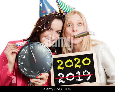 Zwei Frauen, die eine Schiefertafel und eine Uhr auf weißem Hintergrund. Neues Jahr 2020 Konzept. Stockfoto