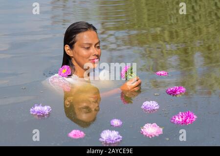 Junge Frau im Wasser mit bunten Blumen Stockfoto