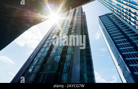 Niedriger Blickwinkel auf gängige moderne Business-Wolkenkratzer mit Sonnenschein. Stockfoto