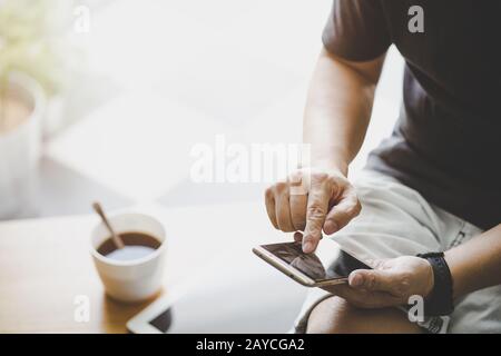 Smartphone in junger Hand mit digitalem Tablet und Kaffee . Stockfoto