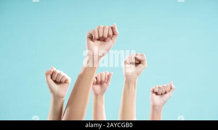 Multiethnische Hand von Männern und Frauen, die vor blauem Hintergrund erhoben wurde Stockfoto