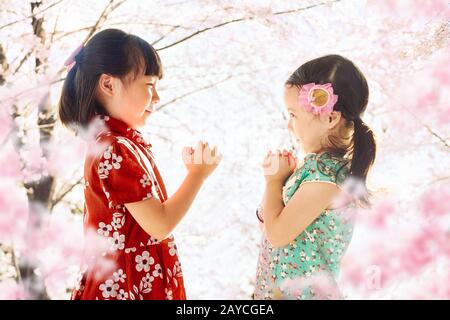 Zwei niedliche Mädchen mit Cheongsam während des chinesischen neuen Jahres Saison. Stockfoto