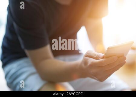 Nahaufnahme der junge Mann das Smartphone mit der mit Sun Flair. Stockfoto
