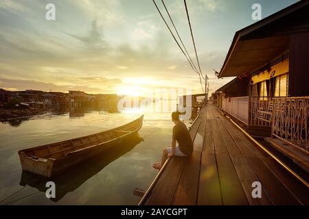 Junge Leute, die den Sonnenaufgang an den Anlegestegen von Penang beobachten Stockfoto