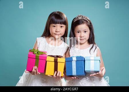 Portrait von zwei kleinen asiatischen schönes Mädchen vier vorliegenden Box auf Vintage blauen Hintergrund. Stockfoto