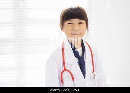 Portrait des kleinen Mädchens, das als Arzt mit einem Stethoskop bekleidet ist. Stockfoto