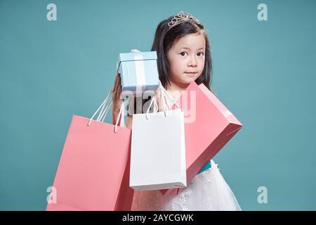 Portrait von kleinen asiatischen schönes Mädchen Betrieb vorhanden, und Shopping Bag auf Vintage blauen Hintergrund. Stockfoto