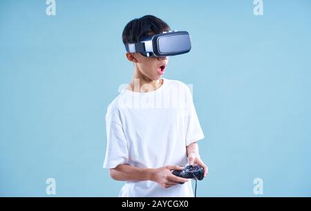 Junge Teenager, die mit einem VR Virtual Reality Headset mit Gamecontroller aufgeregt spielen. Stockfoto