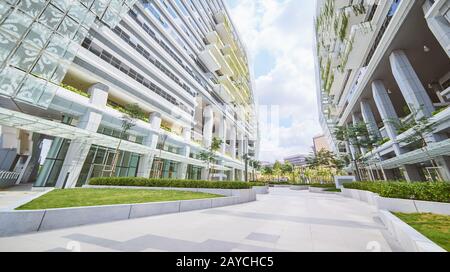 Niedriger Blickwinkel Blick auf das leere Straßenbelag und modernes Bürogebäude mit grünem Öko-Konzept Balkon. Stockfoto