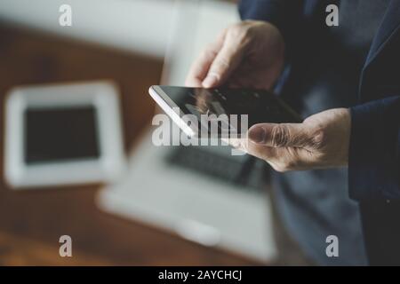Top-Winkel und Nahaufnahme von Geschäftsleuten mit dem Smartphone mit verwackeltem Laptop und digitalem Pad-Hintergrund . Stockfoto