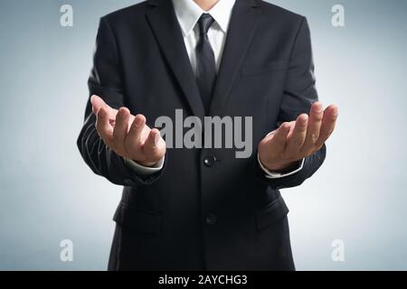 Geschäftsmann in schwarzem Anzug, der helfende Hand ausleiht Stockfoto