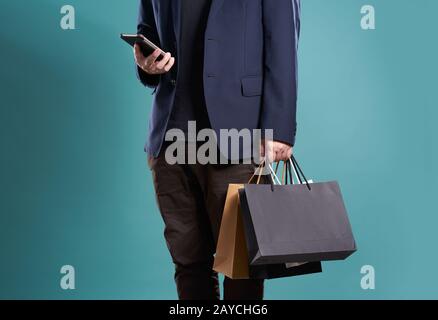 Nahaufnahme von Mann im Anzug mit Smartphone mit Einkaufstaschen Stockfoto