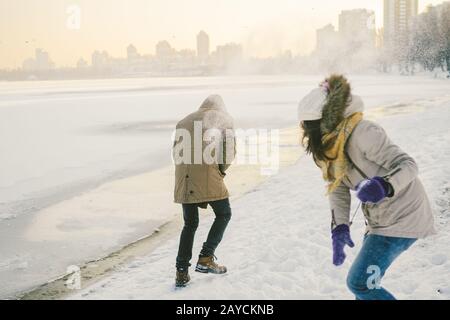 Junge kaukasische Menschen, die sich in heterosexuellen Paaren verliebt haben, haben im Winter ein Datum in der Nähe eines gefrorenen Sees. Aktivurlaub Valentinstag Stockfoto