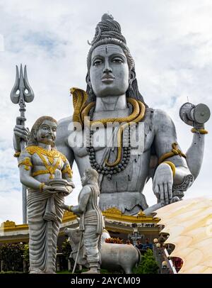 Hindu-Mythen Lord Shiva-Statue, meditiert in Lotus-Pose mit Trident Schlange um den Hals, während ravana dem brahminischen Jungen im Vordergrund Shivling schenkt Stockfoto