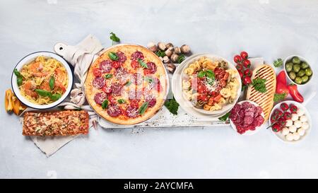 Traditionelle italienische Küche mit Pizza, Pasta, Oliven und Gemüse. Gesunde mediterrane Ernährung. Draufsicht mit Kopierbereich Stockfoto
