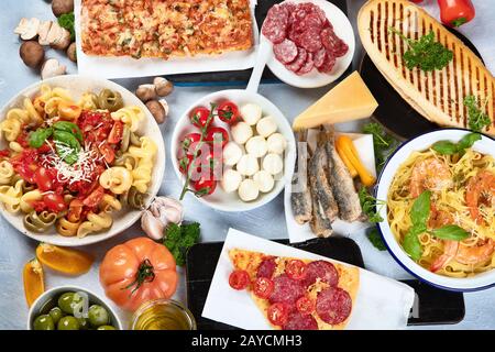 Traditionelle italienische Küche mit Pizza, Pasta, Oliven und Gemüse. Gesunde mediterrane Ernährung. Draufsicht Stockfoto