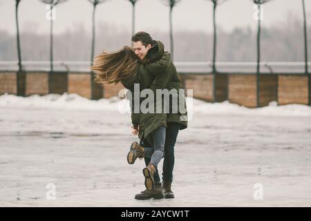 Ein heterosexuelles Paar junge Menschen lieben Studenten einen Mann und eine kaukasische Frau. Im Winter, auf dem mit Eis bedeckten Stadtplatz, Stockfoto