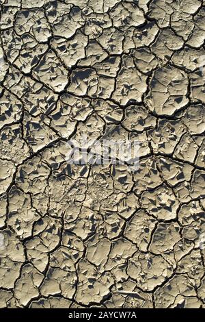 Gerissene Bodenbeschaffenheit. Harte Schatten und Sonne. Getrockneter Boden. Stockfoto