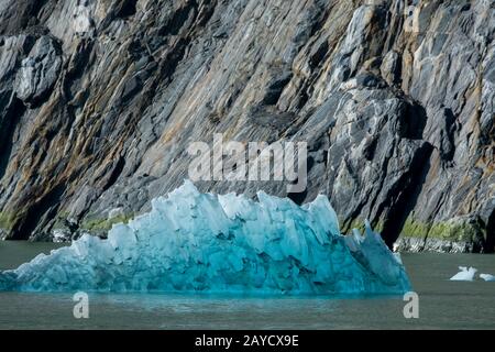 Ein Eisberg vom South Sawyer Glacier, der in Tracy Arm, einem Fjord in Alaska bei Juneau, Tongass National Forest, Alaska, USA, mit dem Granit schwimmt Stockfoto