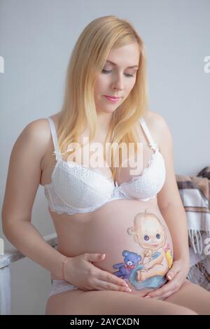 Glückliche schwangere Frau mit einer schönen Zeichnung auf dem Bauch Stockfoto