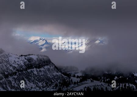 Blick zwischen Wolken auf sonnenbeleuchteten Bergen Stockfoto