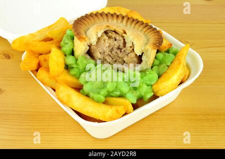 Fleischkuchen und Pommes mit matschigen Erbsen in einem Take-away-Kasten Stockfoto
