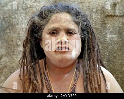 Die indische Hindu-Frau Sadhu (Sadhvi) mit langen Dreadlocks und heiligem Eschen (Vibhuti) auf dem Gesicht und den Schultern stellt sich für die Kamera. Stockfoto