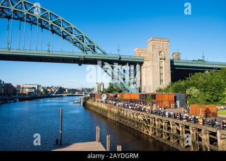 Lebensmittelstände in Gateshead, Newcastle Quayside an einem schönen Sommernachmittag mit den Brücken Tyne und Millennium im Backgro-Viertel Stockfoto