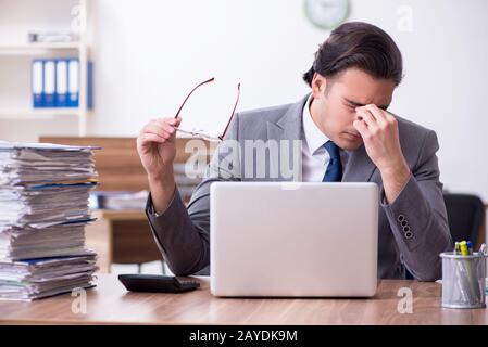 Junge männliche Mitarbeiter mit übermäßiger Arbeit unzufrieden Stockfoto