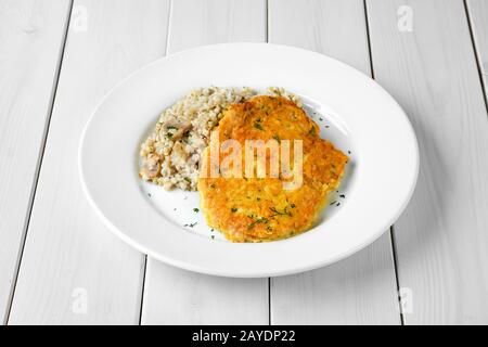 Schnitzel mit grünem Buchweizen auf weißem Holztisch Stockfoto